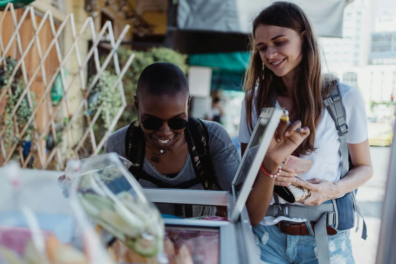 two women standing and looking at a cell phone