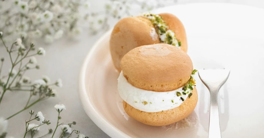 two small desert sandwiches on a plate with a fork