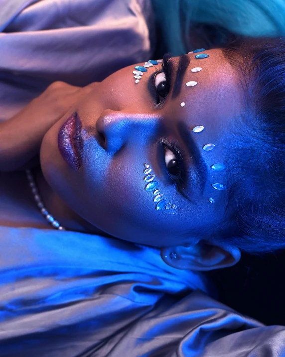 a woman with blue face paint laying on a bed