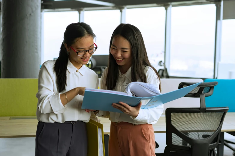 two women look at the blueprint in a large paper