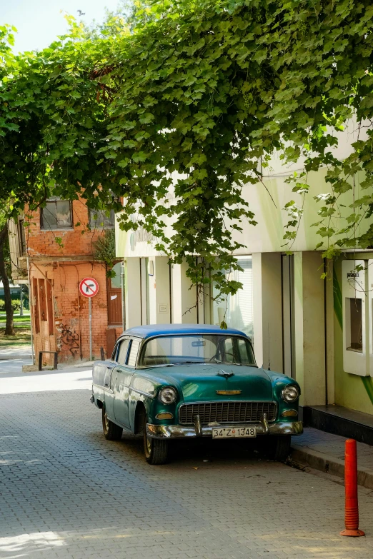 an old green car is parked along the street