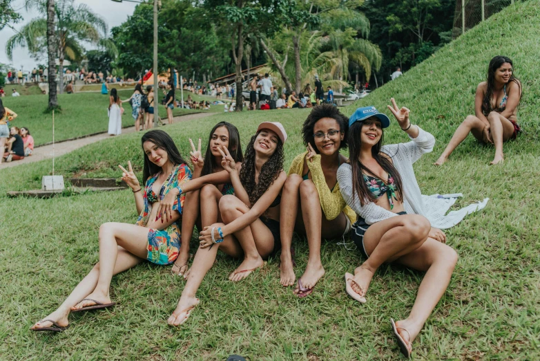 girls are sitting on the grass at a festival