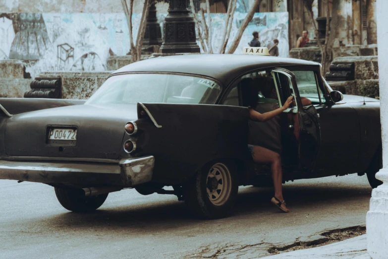 a woman getting out of an old vintage car