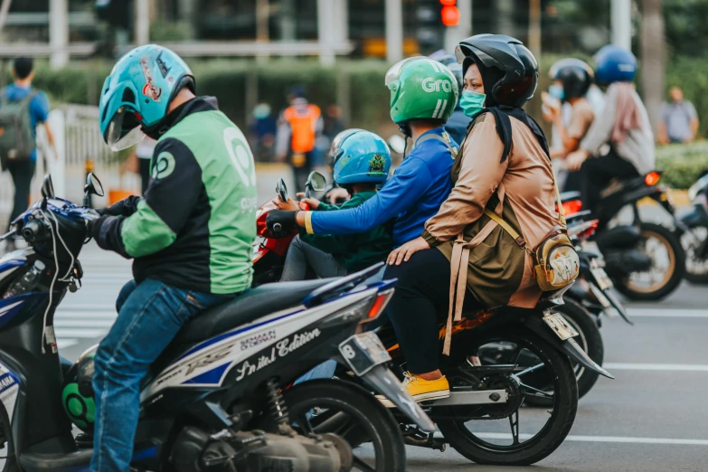 several people riding motorcycles on the street near traffic lights