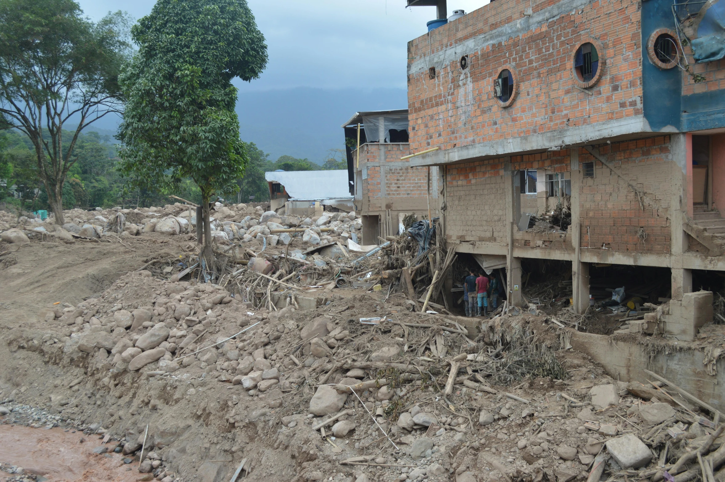 many buildings in rubble with people standing outside