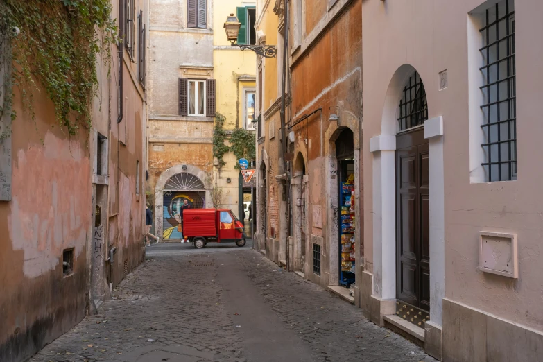 an old red van is traveling down a narrow city street