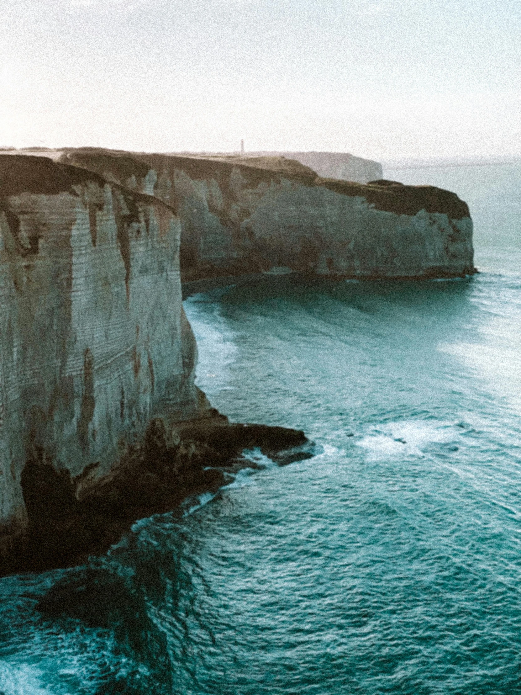 a group of people standing on top of a cliff by the ocean