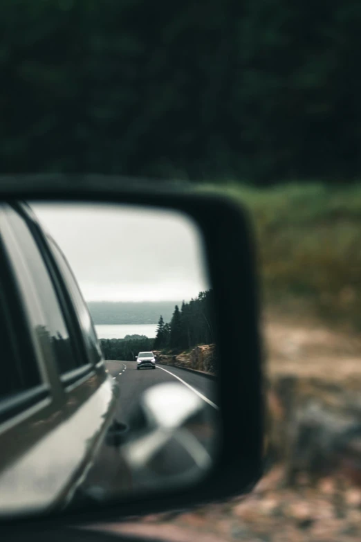 the rearview mirror is reflecting vehicles on the road