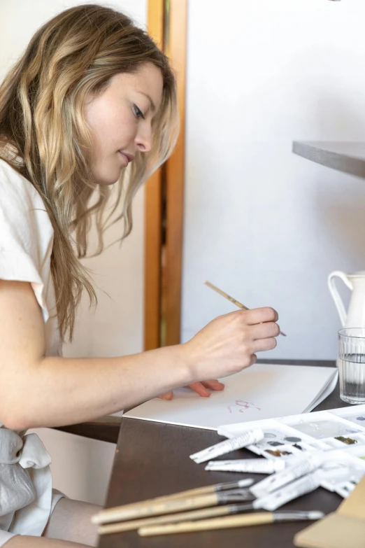 a woman sitting at a table using a pen and paper