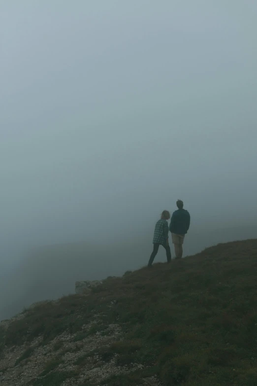 two people walking up a hill while looking at a plane