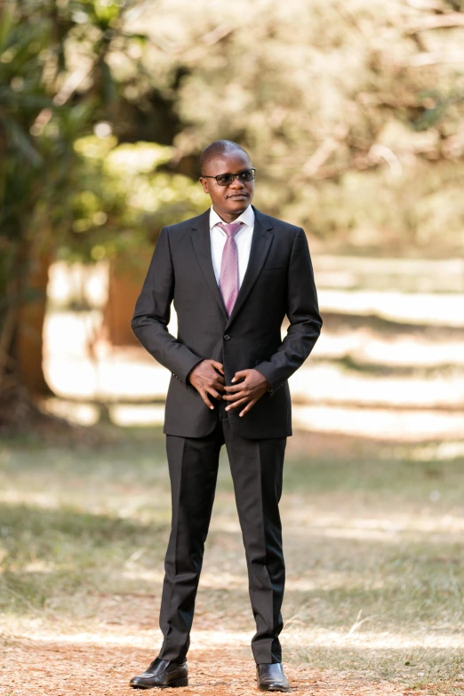 a man standing on a dirt road wearing a suit