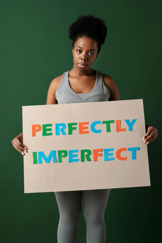 a woman holds up a sign that reads perfectly imperfect