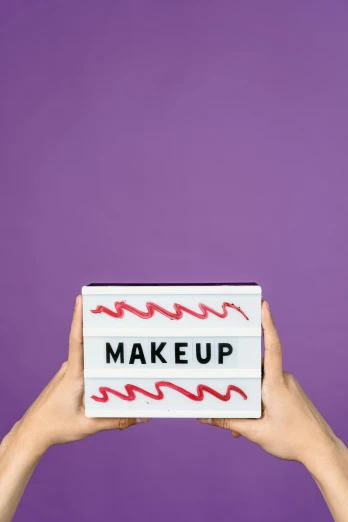 two hands holding up a light box with the word makeup written on it