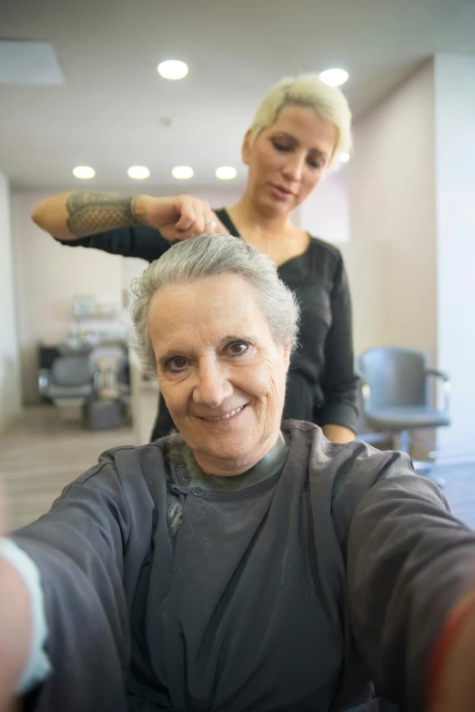 a woman smiles while the woman in the picture stands next to her holding a piece of hair