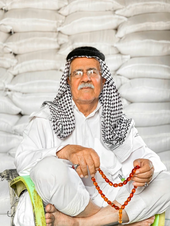 a man sitting on a chair holding a bead necklace