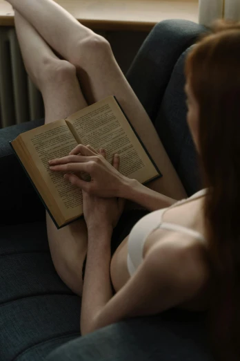 a woman laying on the couch while reading a book