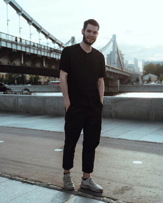 a man standing on a road in front of a bridge