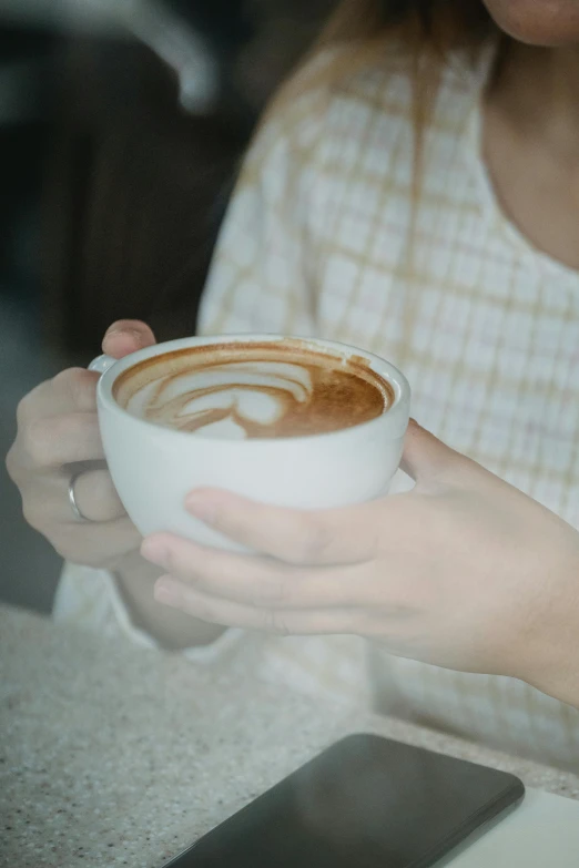 a woman holding a cup of coffee on her left hand