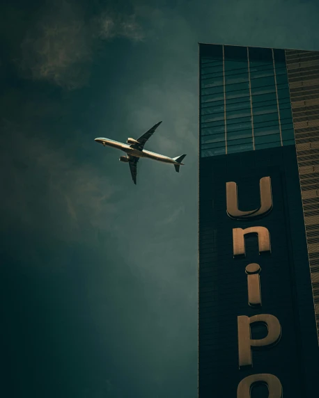 an airplane flying in the air near a tall sign