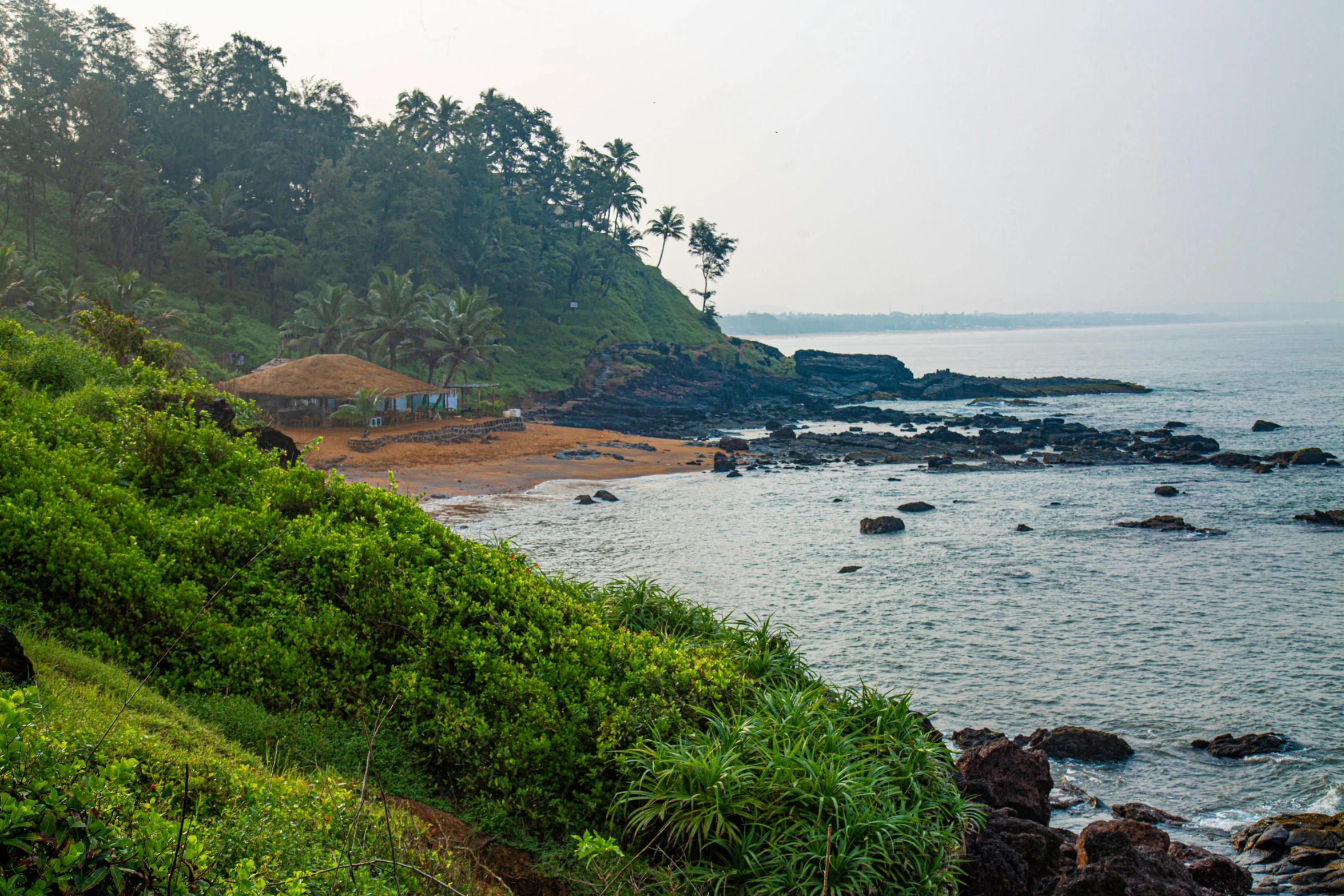 a green hill next to the ocean with water