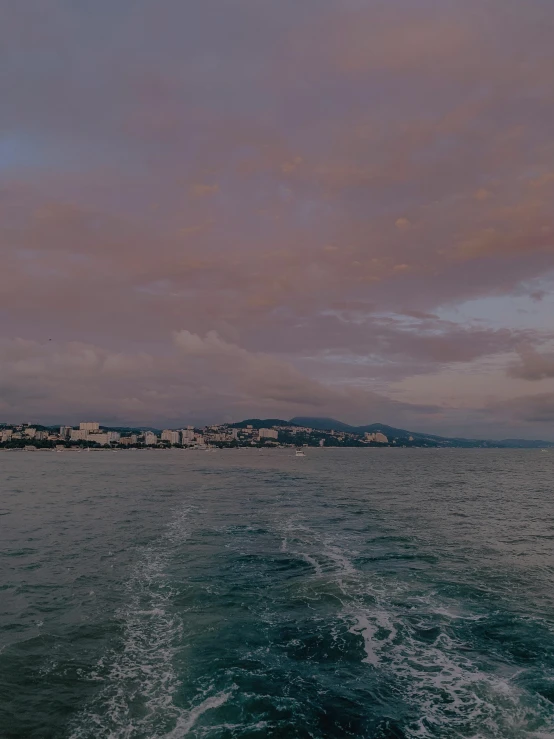 water with a sky full of clouds and a small town in the background