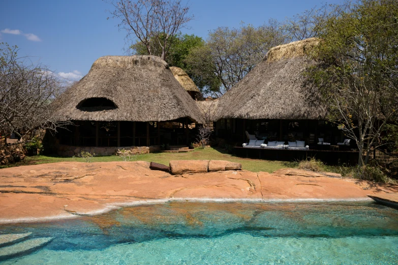 the outdoor dining area has a rock pool and a straw huts like structure