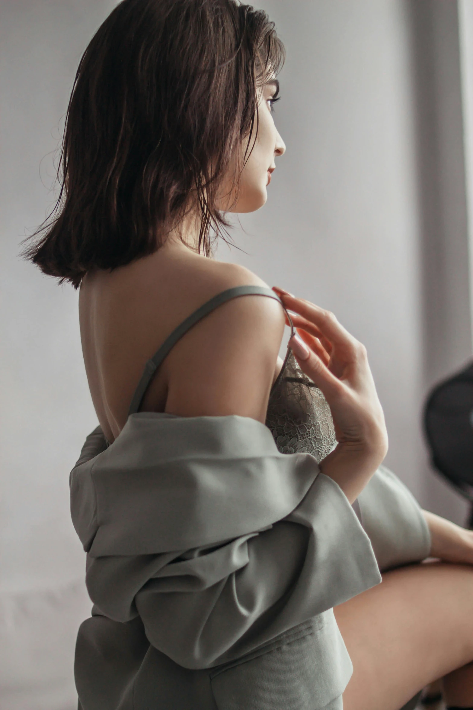 a young woman in a gray top sits on a chair