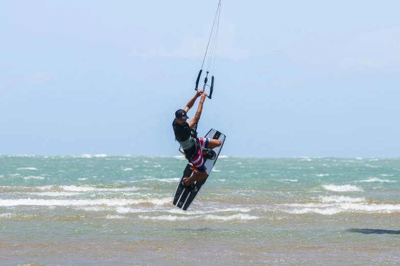 a man wind surfing in the ocean holding on to soing attached to his board