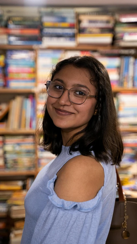 a woman with glasses standing in front of some books