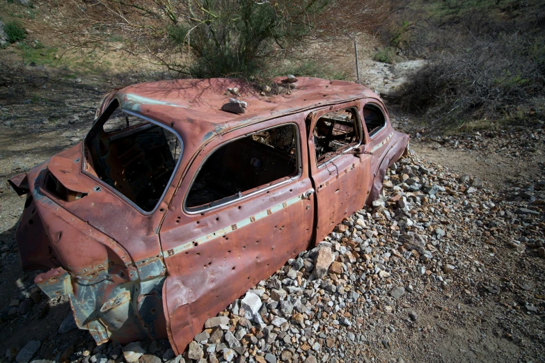 a burnt out car sitting on some rocks