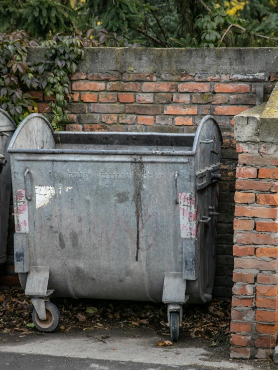 two old gray trash cans sit next to each other