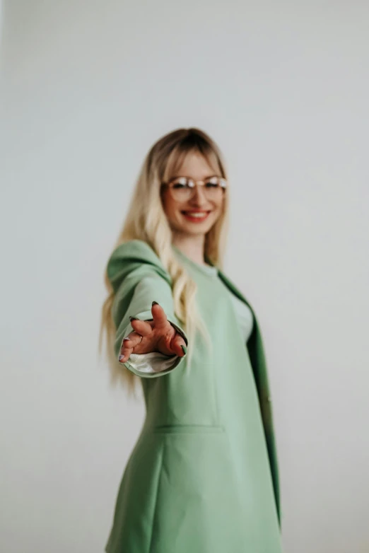 a woman in green wearing glasses pointing towards soing