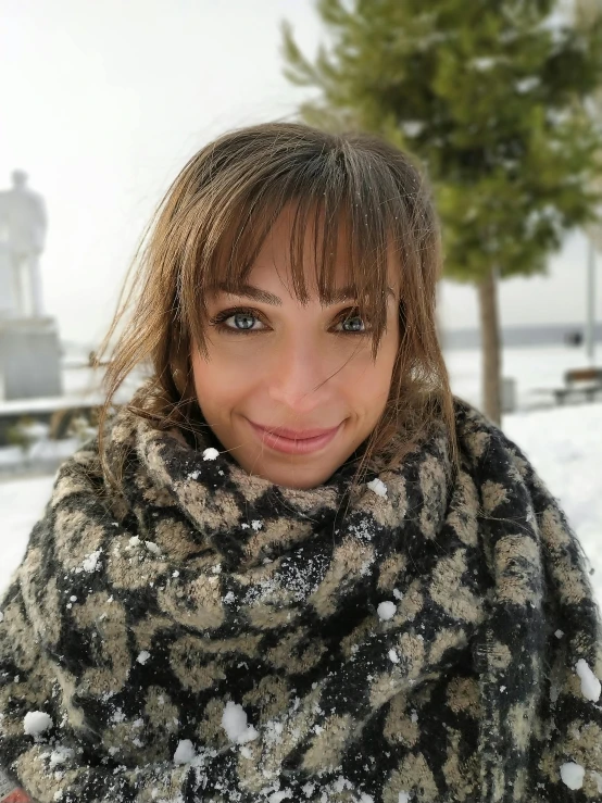 a woman smiling while holding a camera in the snow