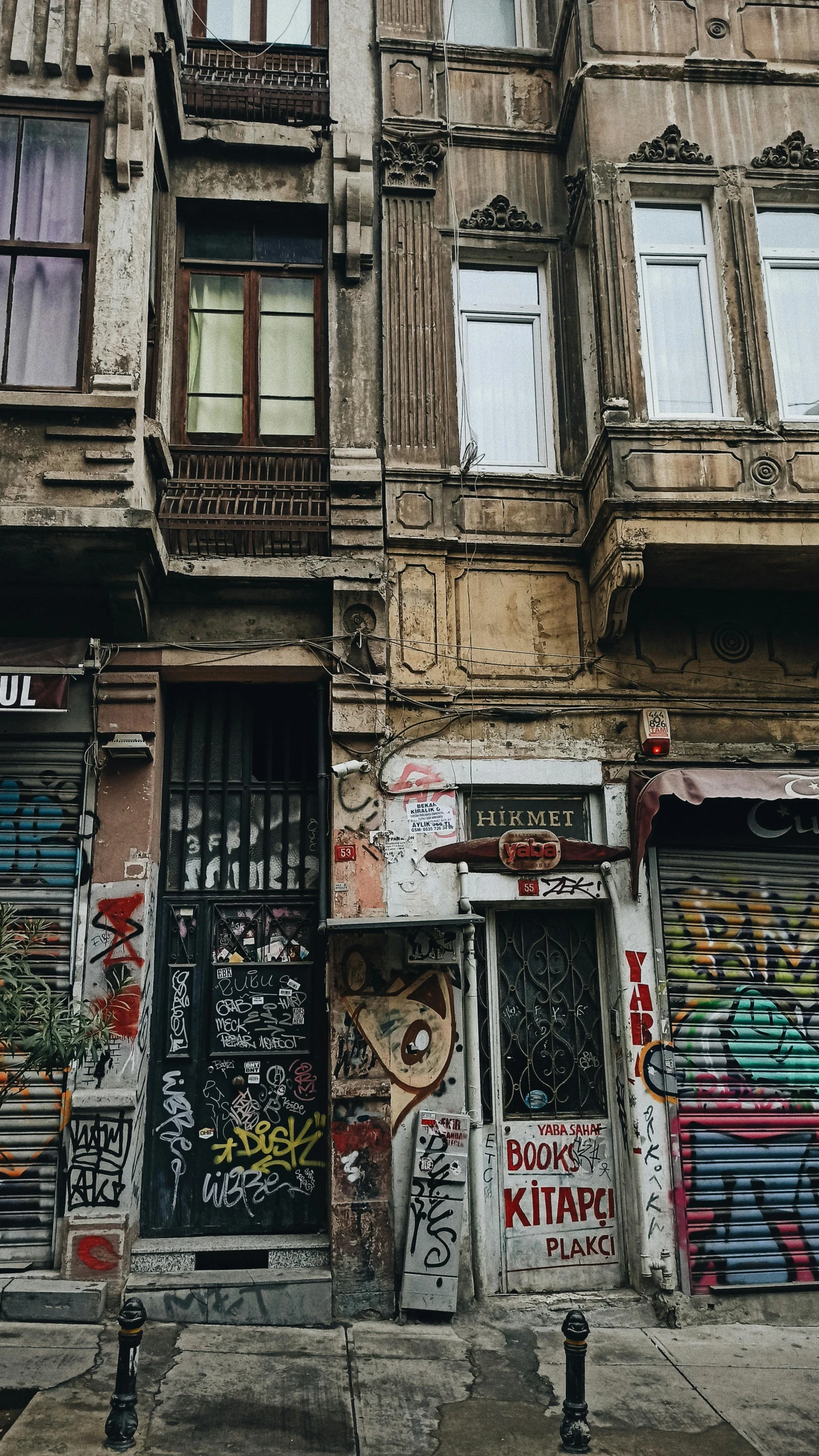 the front entrance of an apartment building with several windows and a graffiti covered facade