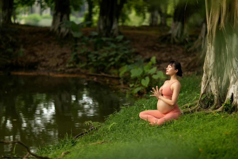 the woman is practicing yoga near the pond