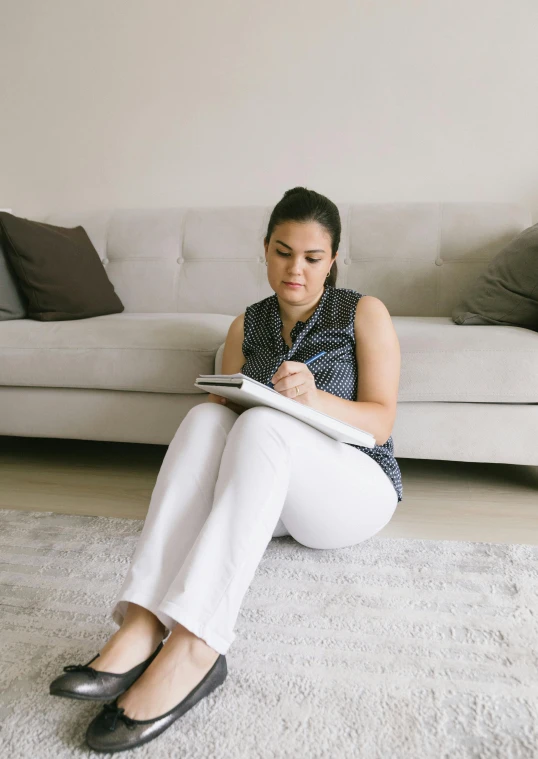 a woman sitting on the ground reading soing