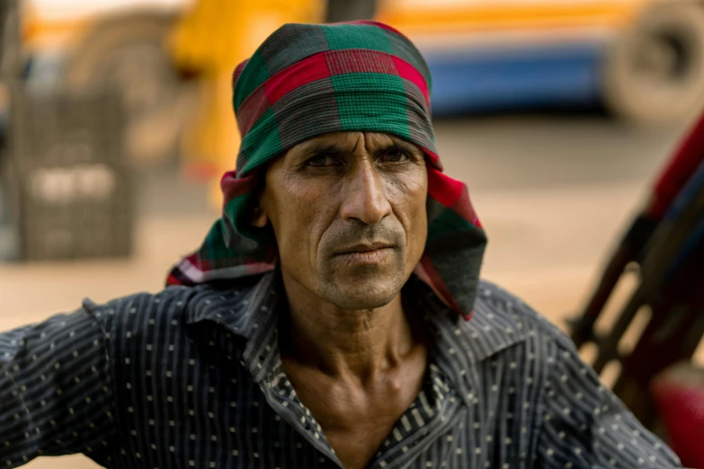 the man wearing a multicolored turban is leaning on a vehicle