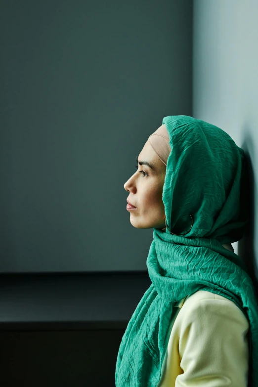 a woman with a scarf on looking out of a window
