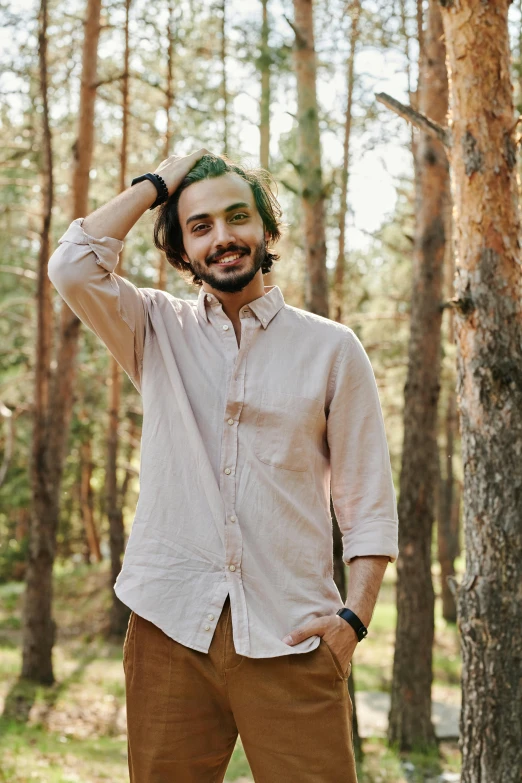 a man standing in the woods wearing brown pants