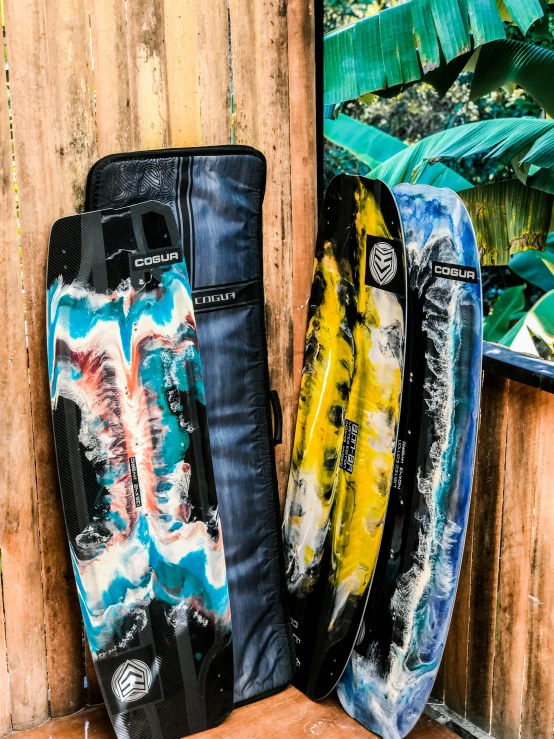 three surfboards against a wooden fence next to each other