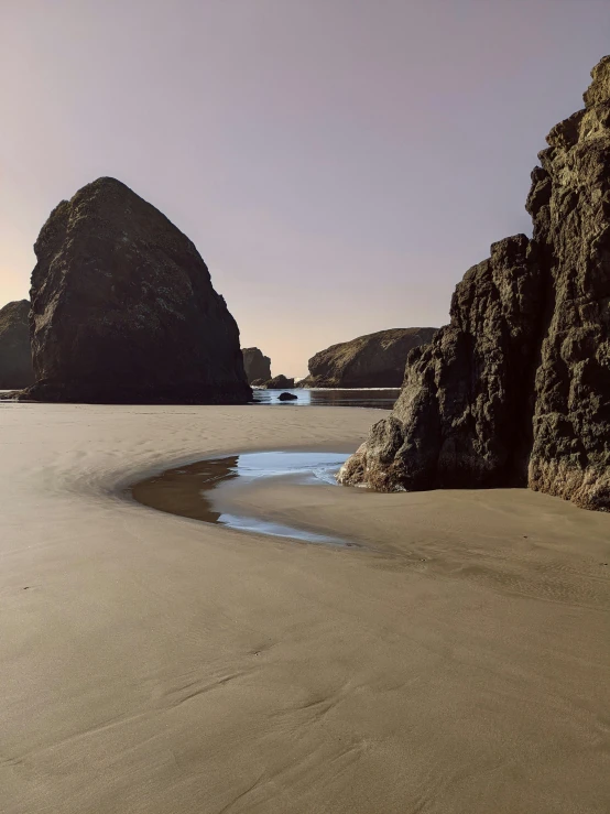 two rock formations near the water at the beach