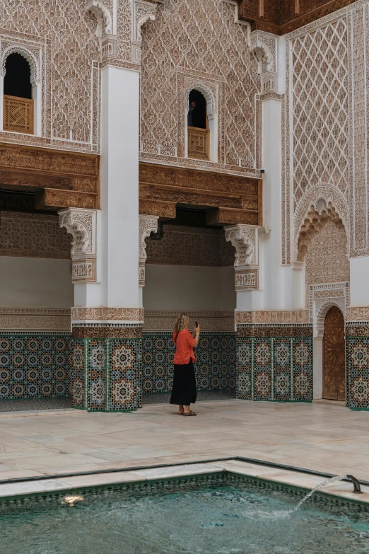 a woman in red stands by a pool