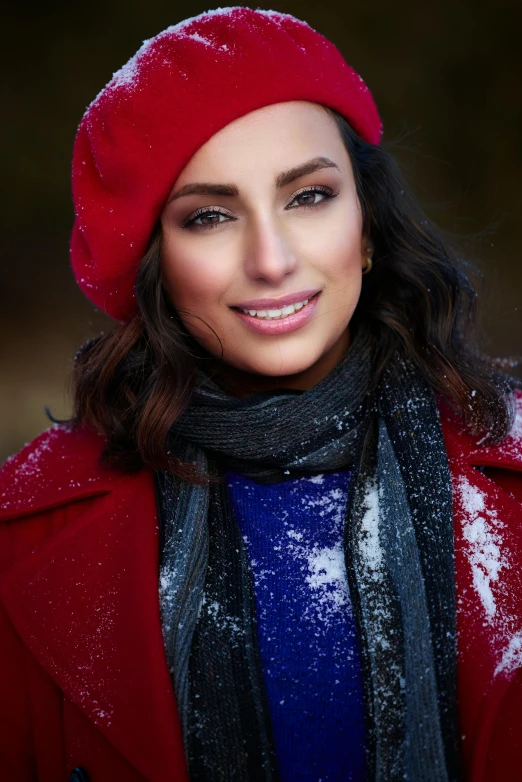 a smiling woman is dressed up in red, she is wearing a woolly coat