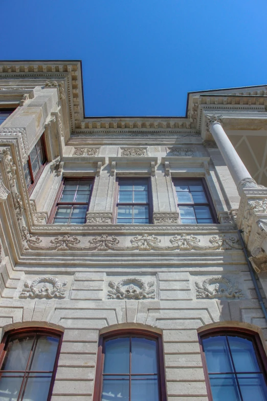 the corner of a white building with many windows and a sky background