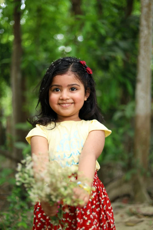 the small girl is smiling while holding a plant