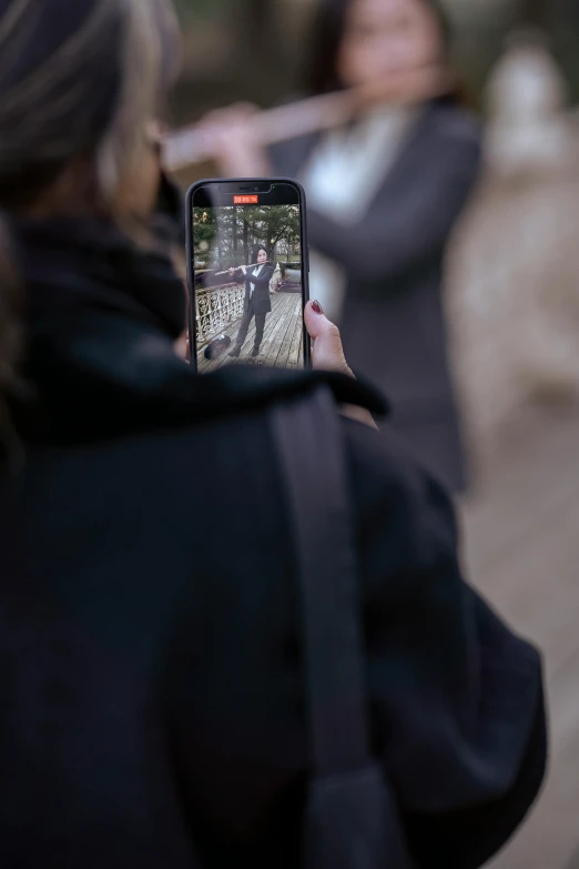 a woman holds up a cell phone while she pographs a bear