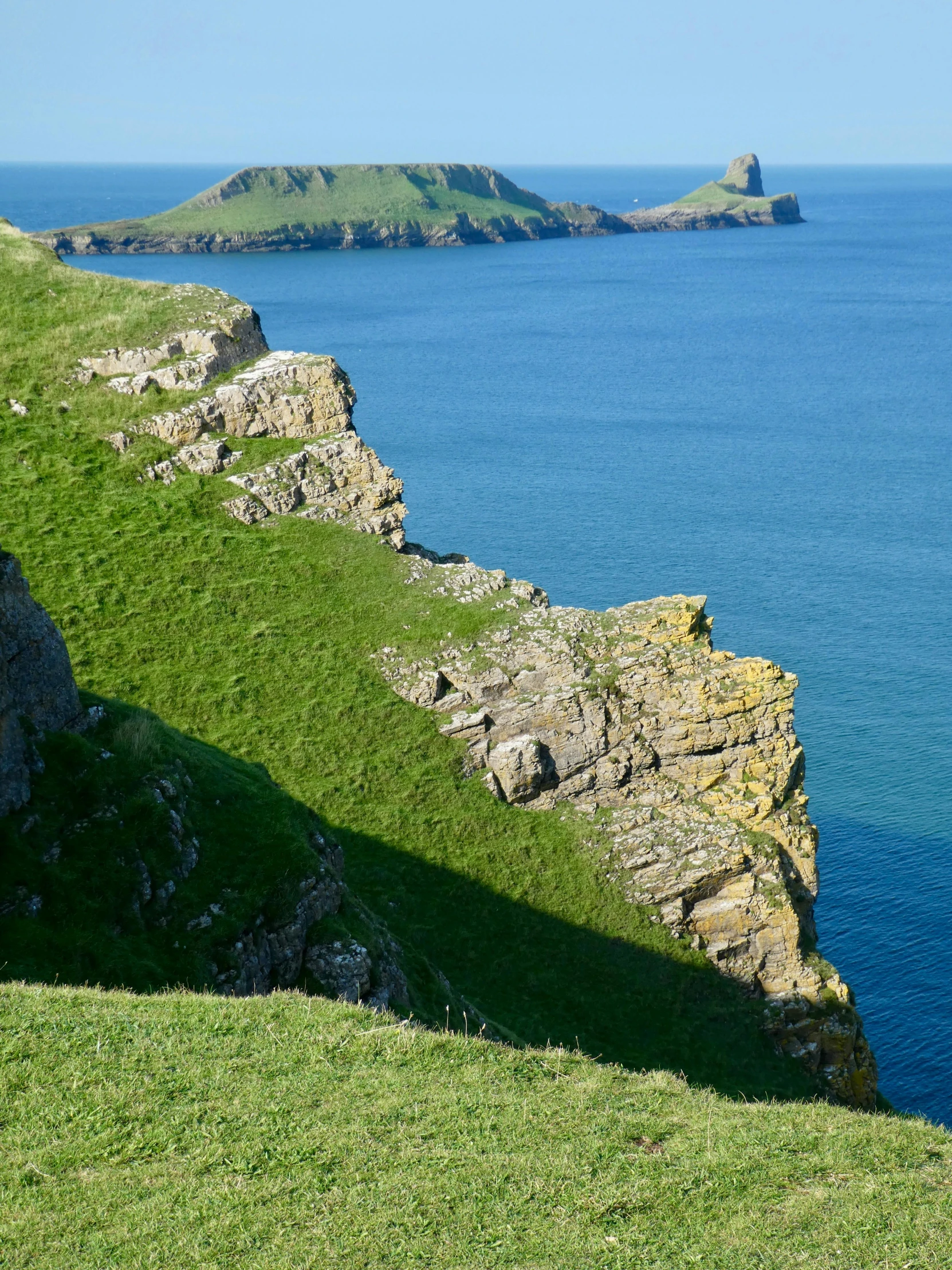 some sheep are sitting on a grassy hill