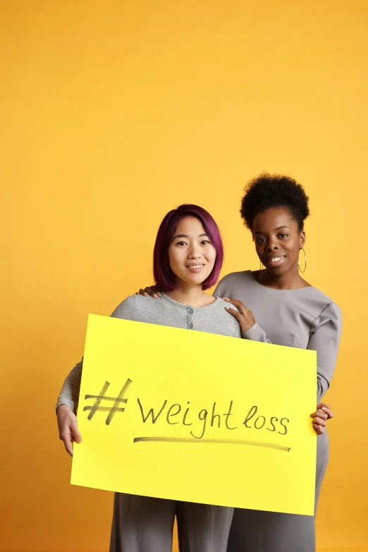 two women are holding a weight loss sign