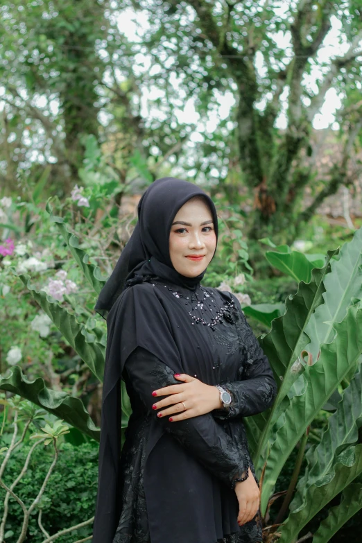 a woman standing next to a leaf covered tree