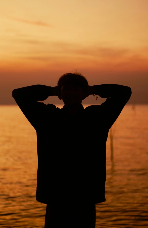 a person standing on the shore of a lake at sunset